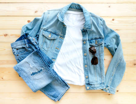 White tshirt mockup and denim jacket jeans on brown wooden background. Template, flat lay
