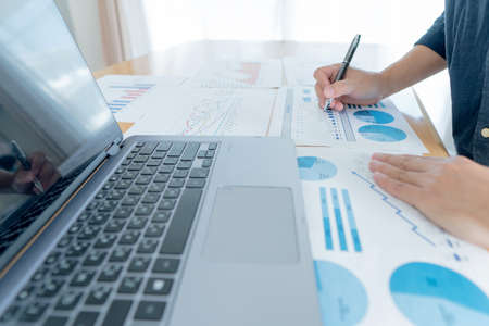 Businessman hand analyzing chart on paper investment charts with laptop. Accounting.