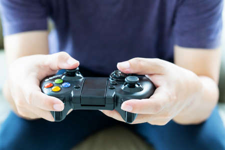 A young man holding game controller playing video games, Selected focus fingers