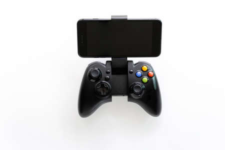 Black gaming joystick with smartphone installed into holder, with blank black screen, turned off....