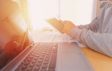 Businessman in casual wear stands beside desk to work at home with taplat. work from home concept.の写真素材