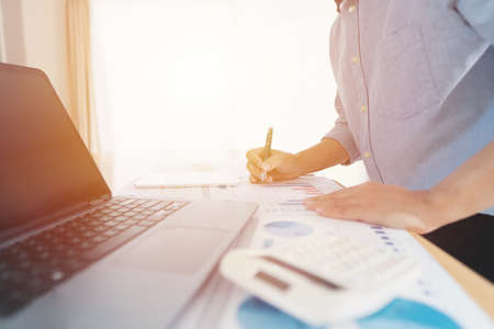 Businessman hand analyzing chart on paper investment charts with laptop. Accounting.の写真素材