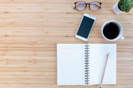 flat lay composition with notebook, pen, coffee, plant, laptop on wood background. Concept top view