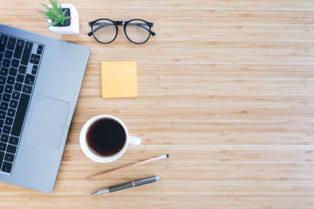 flat lay composition with notebook, pen, coffee, plant, laptop on wood background. Concept top viewの写真素材