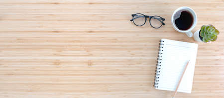 notebook with pencil , glasses, small tree and coffee on old wooden table.Top view. Flat lay.