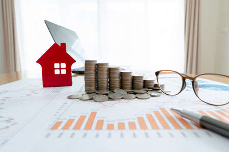 Stacked of Coins and house model , graph ,glasses and laptop, investment concept.の写真素材