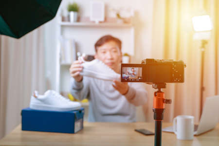 Close up of camera screen. Young male technology blogger recording video blog or vlog review of new shoes at home studio. Blogging, Work from Home concept. Focus on camera screenの写真素材