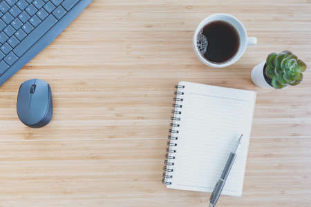 flat lay composition with notebook, pen, coffee, plant, laptop on wood background. Concept top view