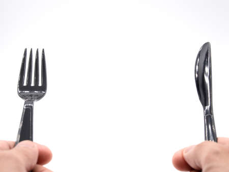Hands holding black plastic fork and knifeの写真素材