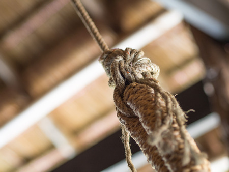 a shot focus on a tied twisted hemp rope hanging from the ceiling blur out the restの写真素材