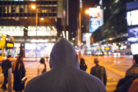 A man in a hood at a crossroads near a road in the cityのeditorial素材