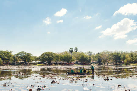 Siem Reap, Cambodia January 20, 2017. Workers clean plants from a pond in a boat