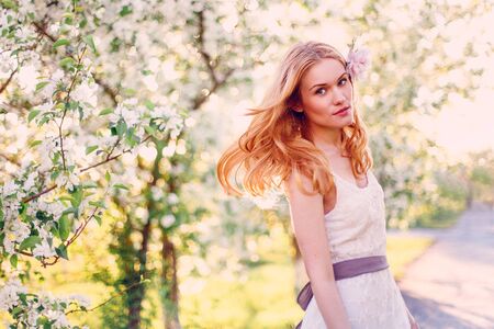 Model with red hair posing in a blooming apple tree.の写真素材