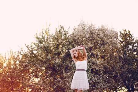 Model with red hair posing in a blooming apple tree.の写真素材