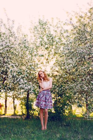 Model with red hair posing in a blooming apple tree.の写真素材