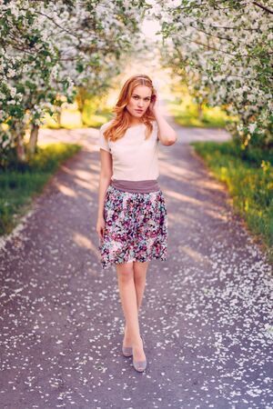 Model with red hair posing in a blooming apple tree.の写真素材