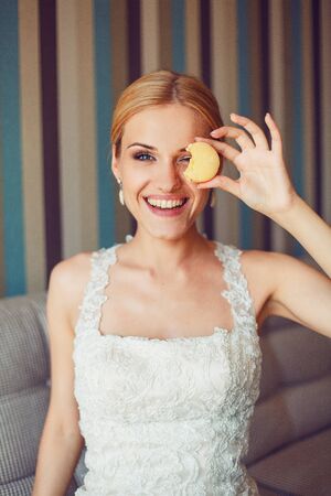 Bride posing with macaroon in handの写真素材