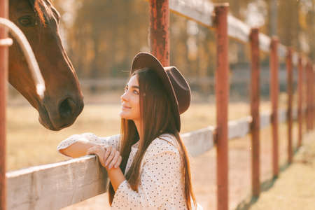 Young girl in dress and hat posing on the farm on a sunny day.