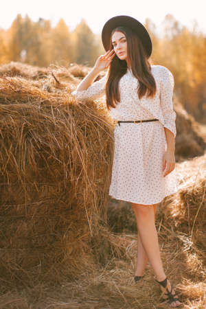 Young girl in dress and hat posing on the farm on a sunny day.の写真素材
