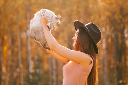 Girl in dress and hat holding a kittenの写真素材