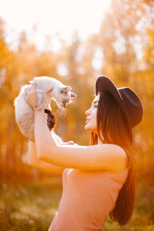 Girl in dress and hat holding a kittenの写真素材