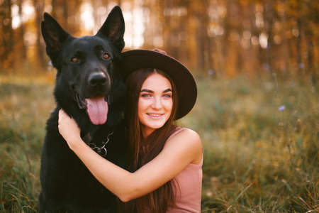 Girl in dress and hat sits with dog in the parkの写真素材