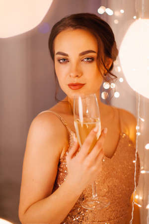 Girl in evening dress posing in the New Year's studio with a glass of champagneの写真素材