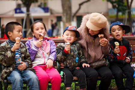HANOI, VIETNAM - JANUARY 13, 2018. Children eat ice cream together with a young mother on a street day offのeditorial素材