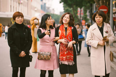 Hanoi, Vietnam. January 13, 2018: A company of beautiful women walk along the street during the day and notice the photographer.のeditorial素材