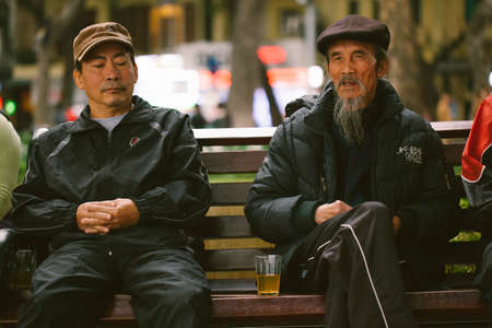 Vietnam. Hanoi. January 13, 2018. A local man and an old man sit on a bench and chat in a park in...