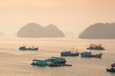 Colorful fishing boats on a sea near to rock islands on sunset. Ha Long Bay, Vietnam.の写真素材