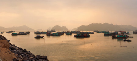 Colorful fishing boats on a sea near to rock islands on sunset. Ha Long Bay, Vietnam.の写真素材