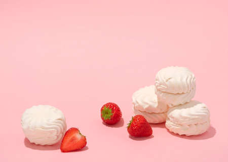 Marshmellows with strawberries on a baby pink background. Soft and airy photo in pastel colours.の写真素材
