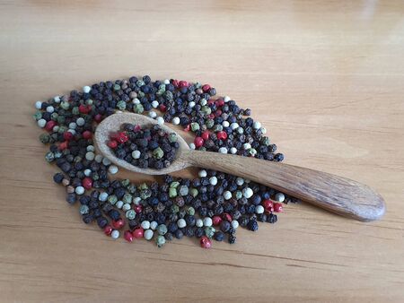 Pepper mix: red, green, white, black on wooden background and wooden spoon, copy spaceの写真素材