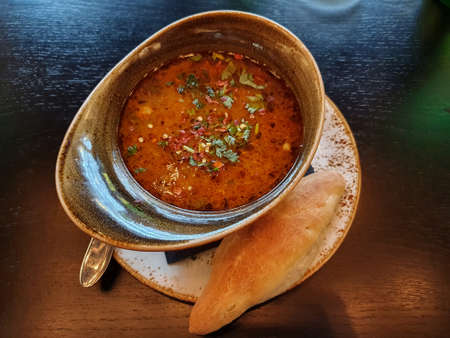 Clay soup bowl and bun. Dark background