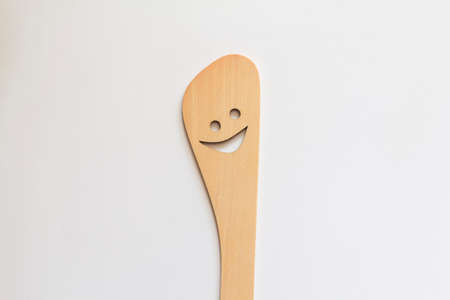 a wooden spatula with a cut-out smile isolated on a white background kitchen utensilsの写真素材