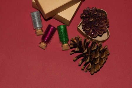 Pattern made of pine cones, shiny glass jars on red background. Flat lay, top view, copy spaceの写真素材
