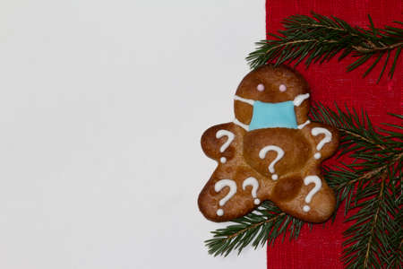 Christmas or winter composition. Red rustic and white background, gingerbread with a face mask with spruce branch decoration. Christmas background, Christmas, winter, new year concept. Flat lay, top view, copy spaceの写真素材