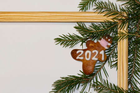 Christmas or winter composition.White background, wooden frame, gingerbread with a face mask and 2021 with spruce branch decoration. Christmas background, Christmas, winter, new year concept. Flat lay, top view, copy space. Food decoration, foodの写真素材