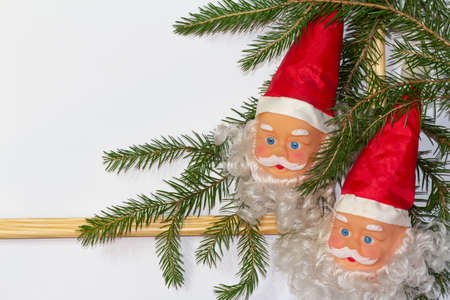 Christmas or winter composition. Santa's head with a red hat, white background, wooden rustic frame, with spruce branch decoration. Christmas background, Christmas, winter, new year concept. Flat lay, top view, copy space, 2021の写真素材