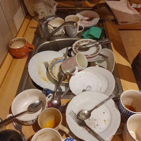 Dirty plates, cups and cutlery in a metal sink.の写真素材
