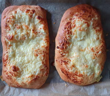 Delicious homemade cheese-stuffed khachapuri on a baking paper background. Georgian cuisine. Food conceptの写真素材
