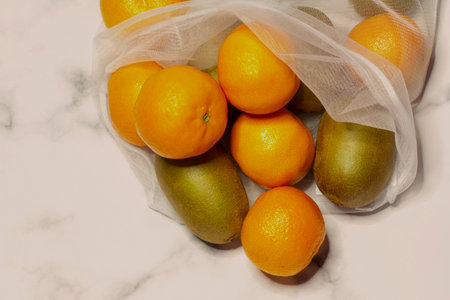 Reusable white mesh shopping bag with vegetables. White-gray marble background. Zero waste concept, no plastic and safe the planet conceptの写真素材