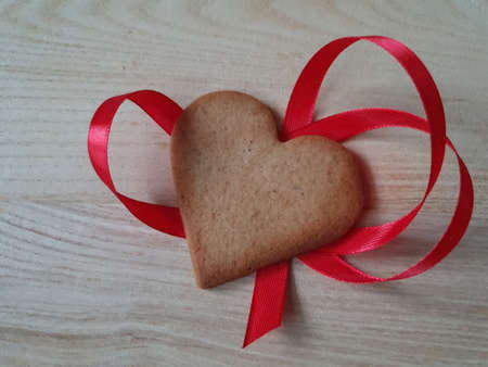 heart-shaped homemade gingerbread decorated with red ribbon on a light wooden background, Valentines Day, greeting card, pastry, Copy space, top view, love concept, Engagement, loveの写真素材