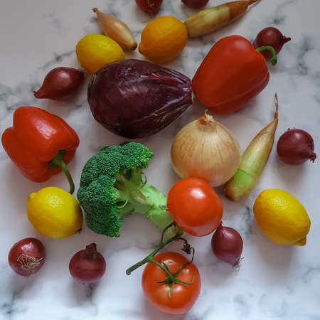 Various vegetables red and yellow onions, broccoli, tomatoes, peppers, lemons on a white-gray marble background. Vitamins, healthy choices, immune system strengthening, antioxidants, food, organic farming, agricultureの写真素材
