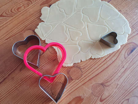 Heart shaped cookie cutter with cut hearts. Wooden rustic background, Valentines Day, greeting card, pastry, Copy space, top view, love concept, Engagement, love, marriageの写真素材