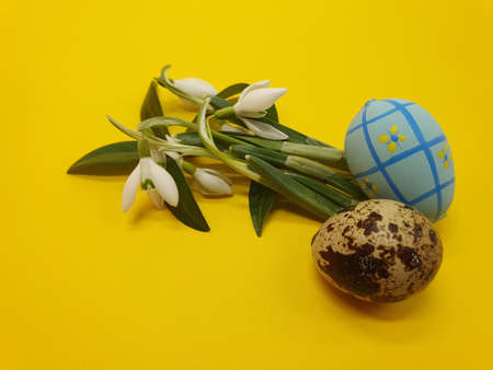 Colorful Easter eggs and spring flowers on a yellow background. Easter greeting, postcard, copy...