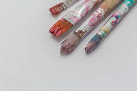 dirty art paint brusches of different sizes and colors on white background, copy space