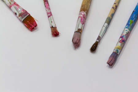 dirty art paint brusches of different sizes and colors on white background, copy space