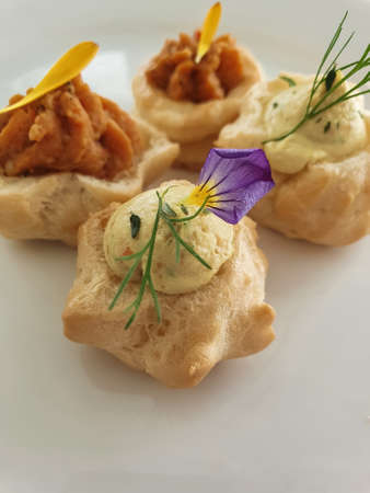 choux pastry appetizer snacks with various creams, decorated with edible flowers. French pastry...